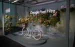 Installation med hylla, hängande ljusskylt, blomster och cykel i eventfärger, Google Pixel 7 Fotografiska