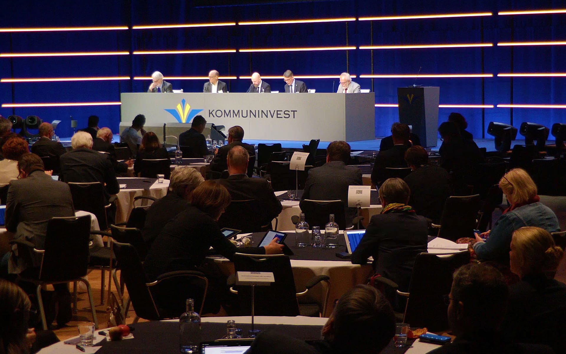 Vinyl-wrapped presidium table for Kommuninvest at Stockholm Waterfront – custom-built with integrated panels and brand graphics.