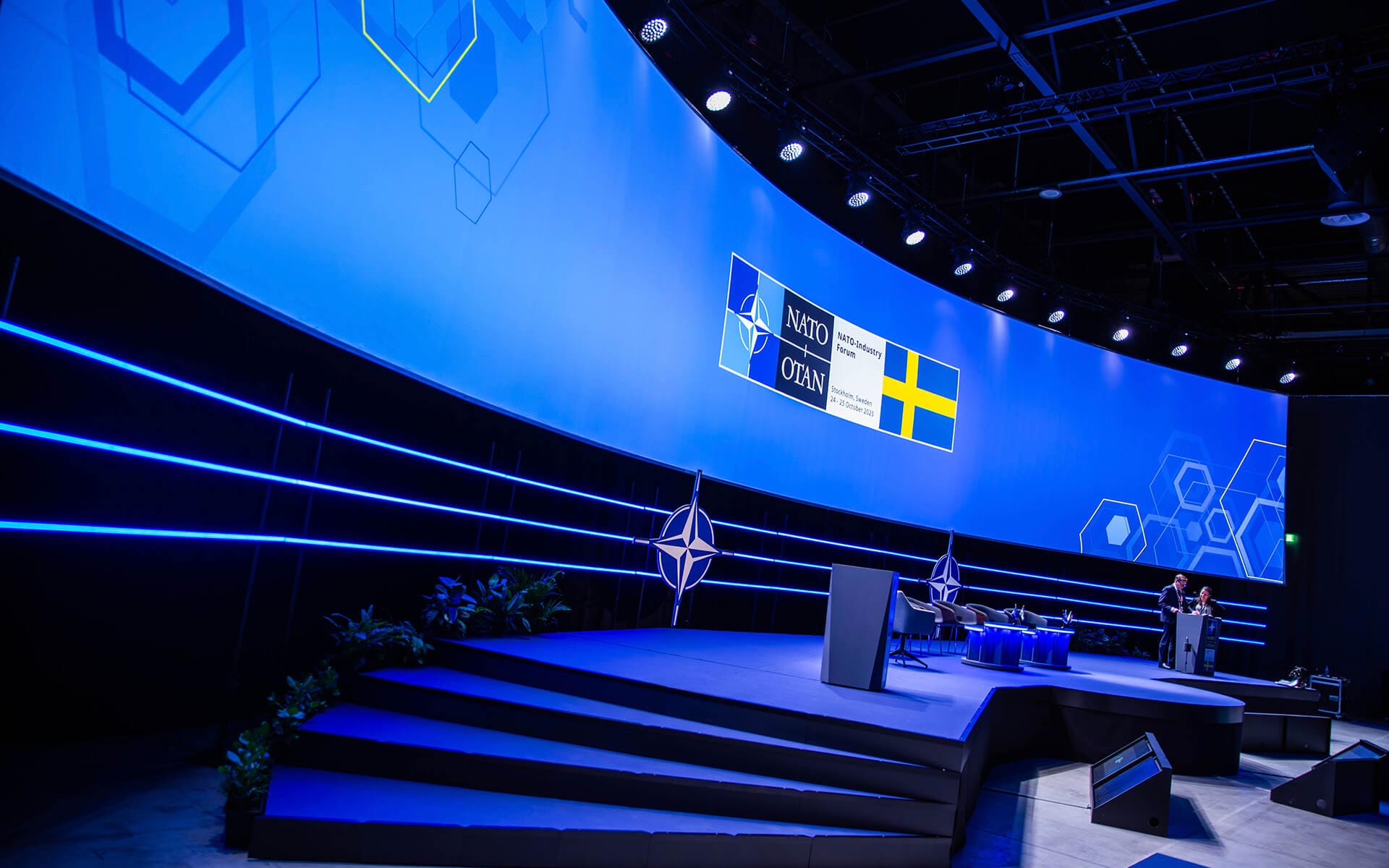 Tre rader Edgetron-armaturer som scenografi under videopanoramat, NATO Industry Forum XPO