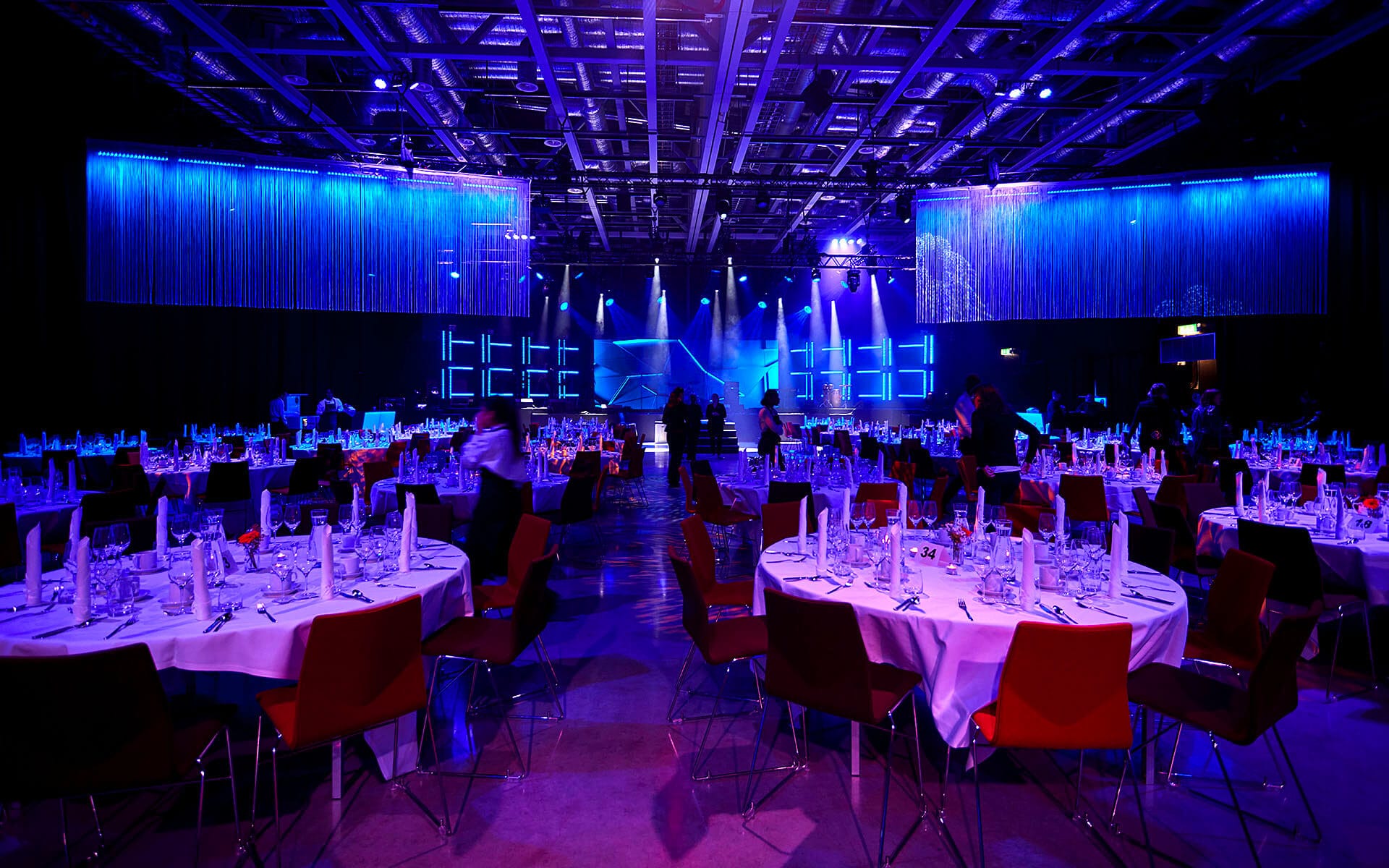 Sandvik TMM 2022 – the dinner section of the event at Strawberry Fields with a stage for live entertainment and full table setting for the seated guests.